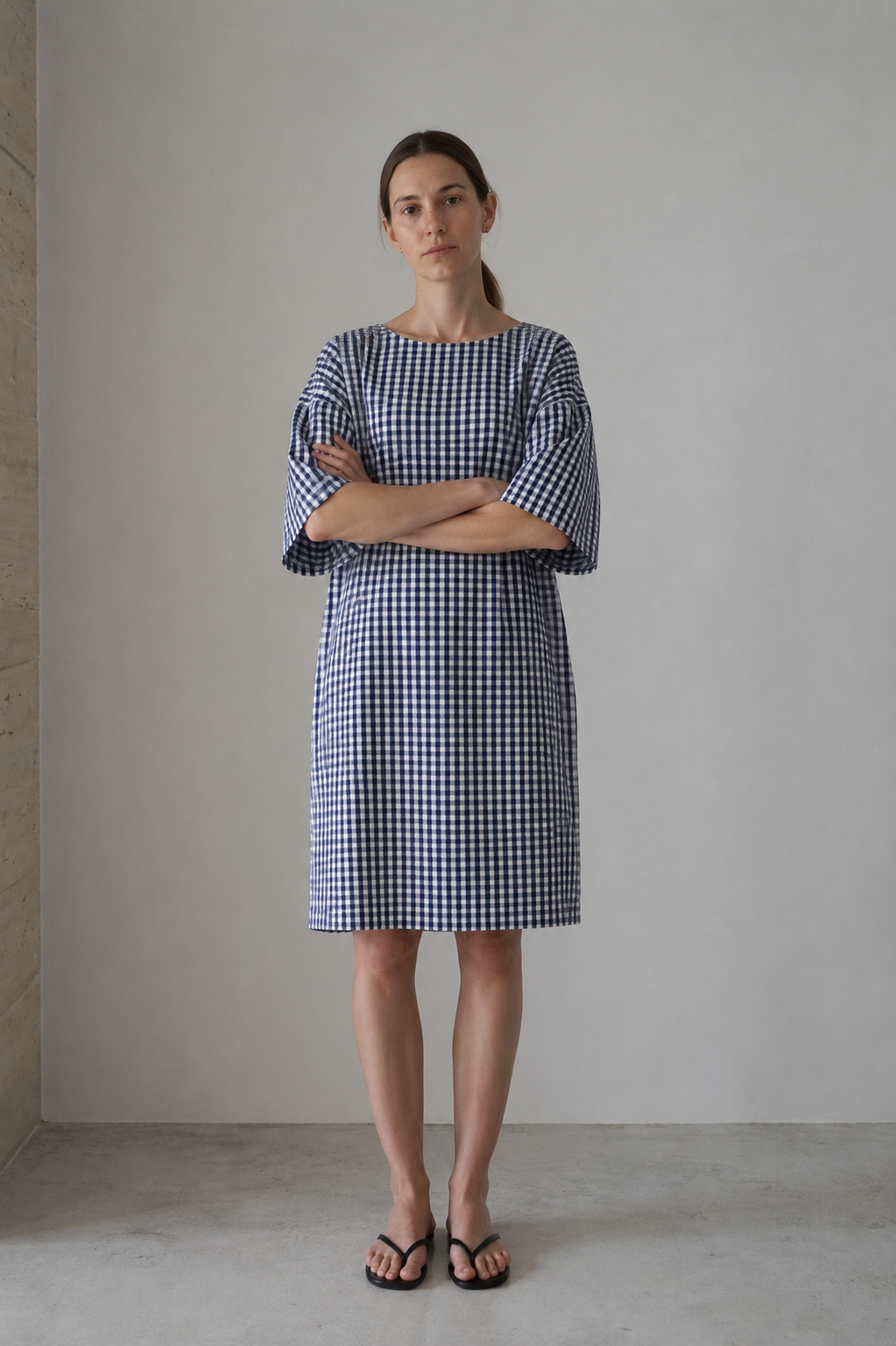 Amance dress in blue gingham, full-length front view with arms crossed