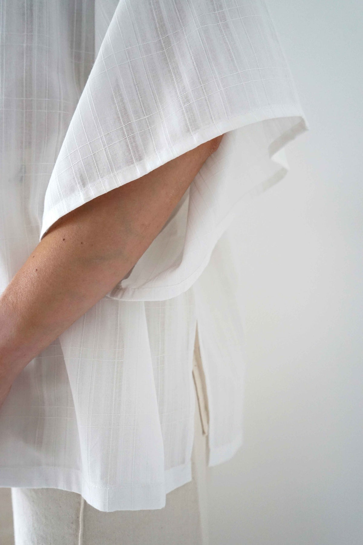 Detail of the wide sleeve and side slit of the Valenza blouse in white