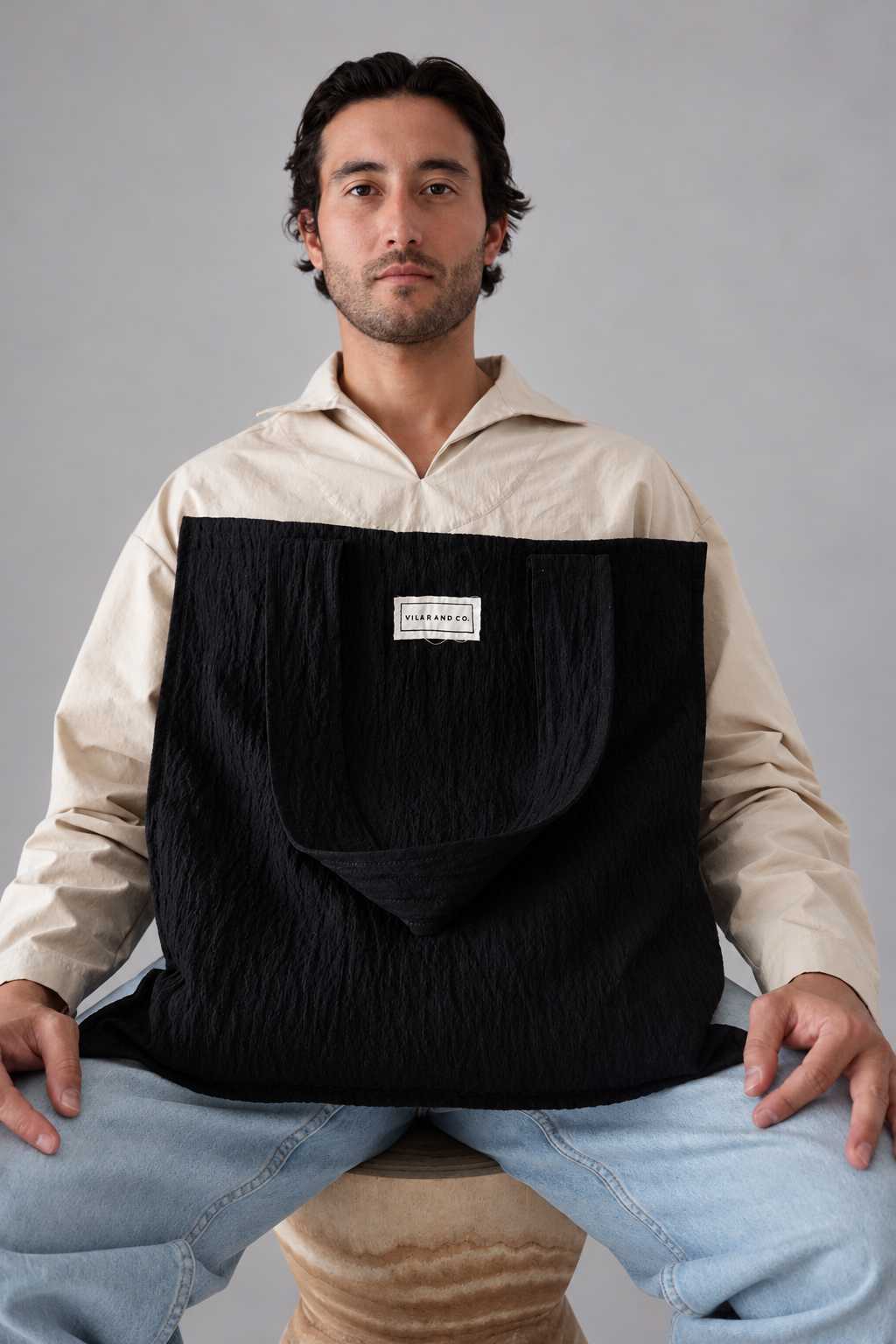Bolso Leiro negro de gran capacidad, mostrado de frente con modelo sentado